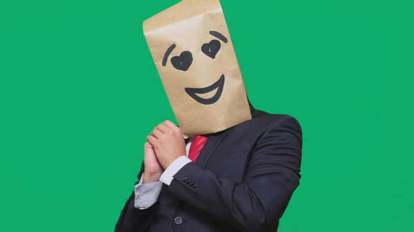 concept of emotions, gestures. a man with paper bags on his head, with a painted emoticon, smile, joy, love eyes.