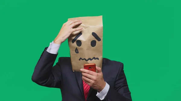 Concetto di emozione, gesti. un uomo con un pacco in testa, con un sorriso dipinto che piange, triste, che parla al telefono — Foto Stock
