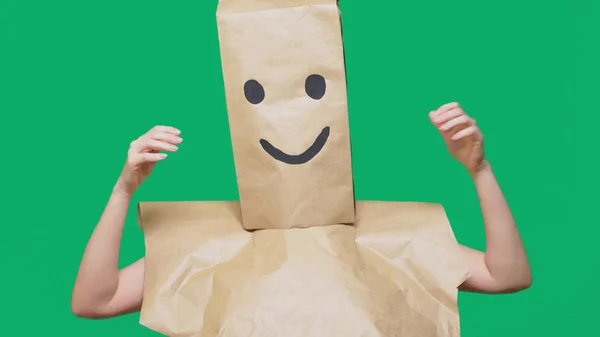 Conceito de emoções, gestos. um homem com sacos de papel na cabeça, com um emoticon pintado, sorriso, alegria — Fotografia de Stock