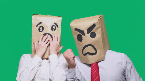 The concept of emotions and gestures. Two people in paper bags with smiles. Aggressive smiley swears. Second scared