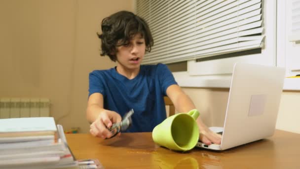 Fiú tinédzser öntötte a teát a laptop. csinál házi feladatot, online tanulás, 4 k közelképekhez, — Stock videók