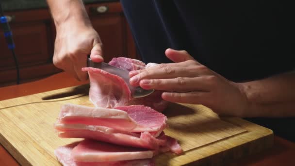 Человек режет замороженное мясо ножом в замедленной съемке. 4k крупный план — стоковое видео