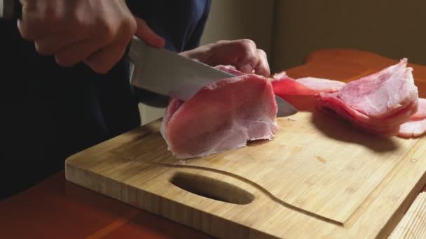 Чоловік ріже сире заморожене м'ясо ножем у повільному русі. 4k крупним планом — стокове відео