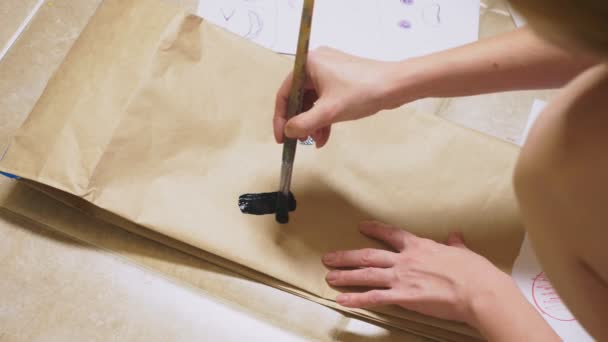 Девушка рисует кисточкой на бумажных пакетах различные эмоции. Концепция эмоций в смайликах — стоковое видео