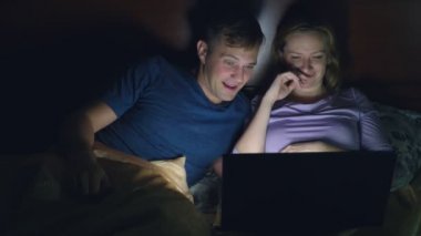 Çift, erkek ve kadın, bir dizüstü bilgisayarda bir yatak yatak odası yatmadan önce bir film izlerken. heyecan verici bir film seyrederken, seyirci ilgi ile çeşitli duyguların yaşandığı izliyor.