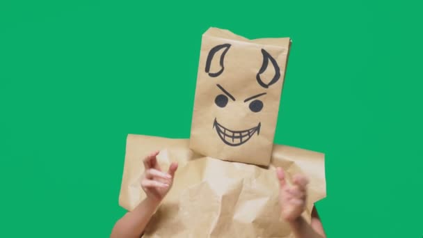 Concept of emotion, gestures. a man with a package on his head, with a painted smiley angry, sly, gloating, devil — Stock Video