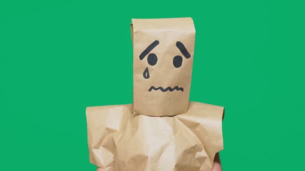 Concept van emotie, gebaren. een man met een pakket op zijn hoofd, met een geschilderde smiley huilen, verdrietig — Stockvideo
