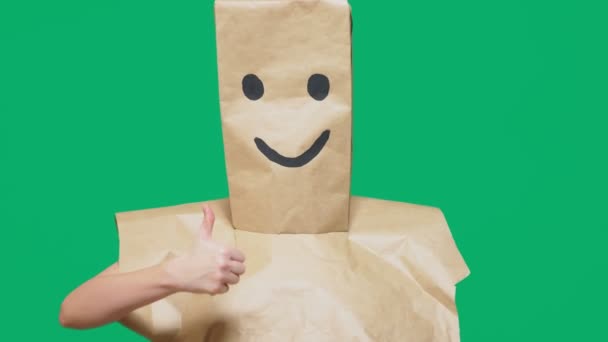 Концепция эмоций, жестов. человек с бумажными пакетами на голове, с раскрашенным смайликом, улыбкой, радостью — стоковое видео