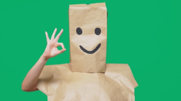 Concept of emotions, gestures. a man with paper bags on his head, with a painted emoticon, smile, joy — Stock Video