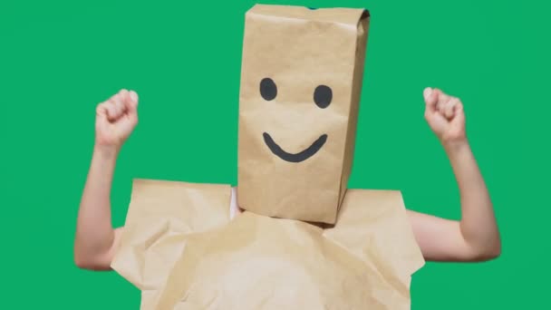Αντίληψη των συναισθημάτων, χειρονομίες. ένας άνθρωπος με χάρτινες σακούλες στο κεφάλι του, με ζωγραφισμένα φατσούλα, χαμόγελο, χαρά — Αρχείο Βίντεο