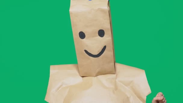 Concepto de emociones, gestos. un hombre con bolsas de papel en la cabeza, con un emoticono pintado, sonrisa, alegría — Vídeos de Stock