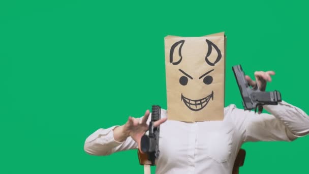Concept van emotie, gebaren. een man met een pakket op zijn hoofd, met een geschilderde smiley boos, sluwe, leedvermaak, duivel, pistolen in handen — Stockvideo