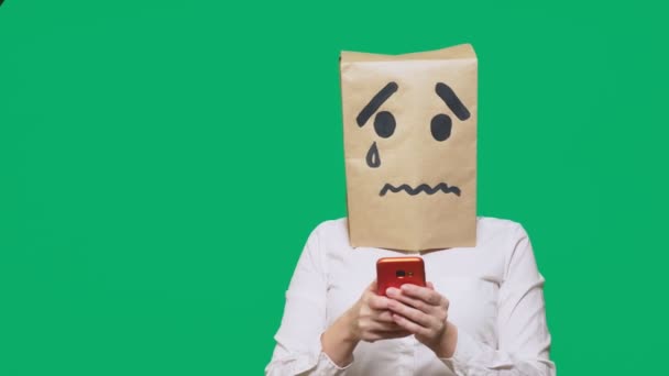 Концепция эмоций, жестов. мужчина с пакетом на голове, с нарисованной надписью плачет, грустит, разговаривает по телефону — стоковое видео