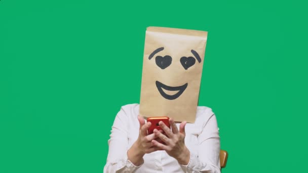 Pojmu emoce, gesta. muž s papírové sáčky na hlavě, s malovanými emotikonu, úsměv, radost, láska. mluví o mobilní telefon — Stock video