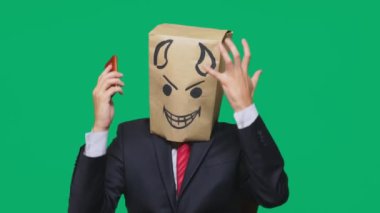 duygular, jest kavramı. haset, bir cep telefonu üzerinde konuşurken bir adam ile bir boyalı siyah gülen surat, şeytan, kurnaz, kafasına bir paketi ile.