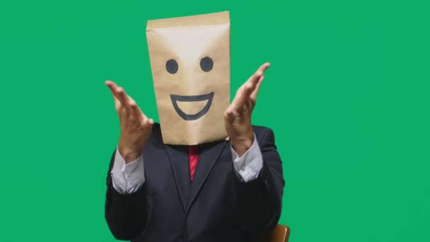 Konzept der Emotionen, Gesten. ein Mann mit Papiertüten auf dem Kopf, mit einem aufgemalten Emoticon, Lächeln, Freude — Stockvideo