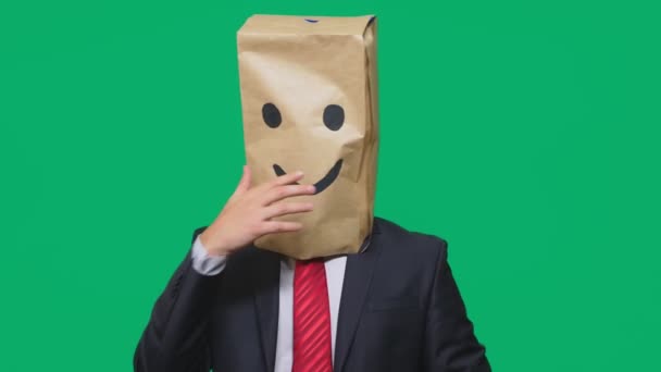 Concepto de emociones, gestos. un hombre con bolsas de papel en la cabeza, con un emoticono pintado, sonrisa, alegría — Vídeos de Stock