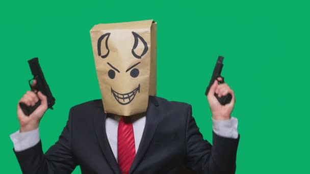 Konzept der Emotion, Gesten. ein Mann mit einem Paket auf dem Kopf, mit einem aufgemalten Smiley wütend, listig, schwärmerisch, Teufel, Pistolen in der Hand — Stockvideo