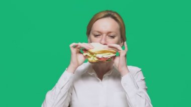 iş kadını yeşil bir arka plan üzerinde bir sandviç yeme. Hızlı öğle yemeği kavramı.