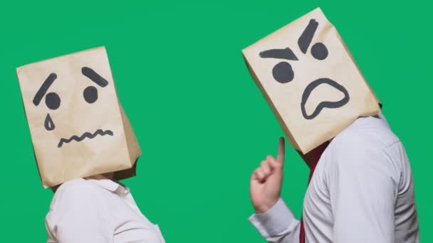 El concepto de emociones y gestos. Dos personas en bolsas de papel con emoticonos. Sonriente agresivo jura. El segundo llora triste — Vídeo de stock