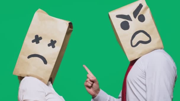El concepto de emociones y gestos. Dos personas en bolsas de papel con emoticonos. Sonriente agresivo jura. El segundo le escucha fatigado. — Vídeos de Stock