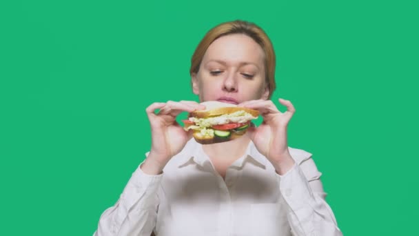 Zakenvrouw eten van een boterham op een groene achtergrond. snelle lunch concept. — Stockvideo