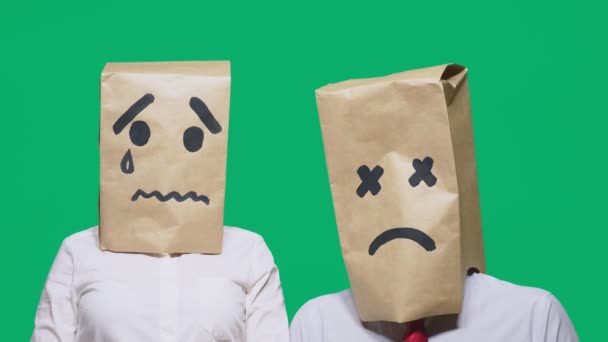 Concepto de emociones, gestos. un par de personas con bolsas en la cabeza, con un emoticono pintado, triste, llorando, cansado — Vídeos de Stock