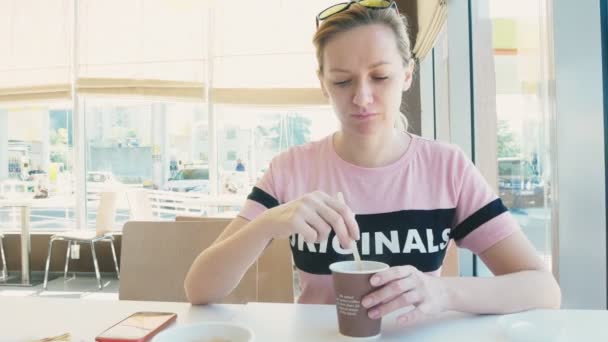 Mooie vrouw een broodje eten en drinken koffie in een café fastfood. fastfood. — Stockvideo