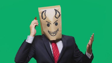 duygular, jest kavramı. haset, bir cep telefonu üzerinde konuşurken bir adam ile bir boyalı siyah gülen surat, şeytan, kurnaz, kafasına bir paketi ile.