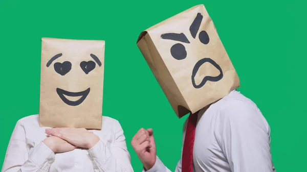 Conceptul de emoții și gesturi. Doi oameni în saci de hârtie cu un zâmbet. Zâmbetul agresiv jură. Al doilea se uită la el în ochii dragostei. . — Fotografie, imagine de stoc