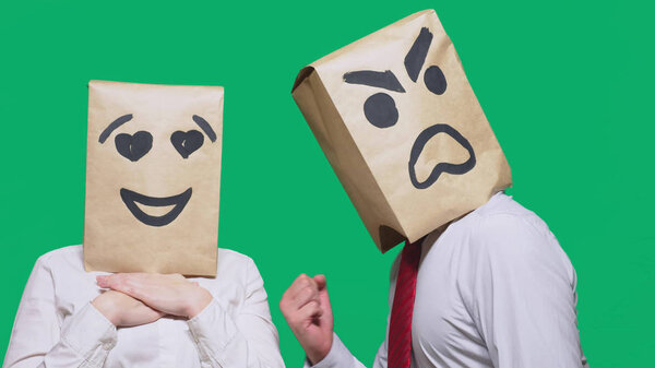 The concept of emotions and gestures. Two people in paper bags with a smile. Aggressive smiley swears. The second looks at him in love eyes.