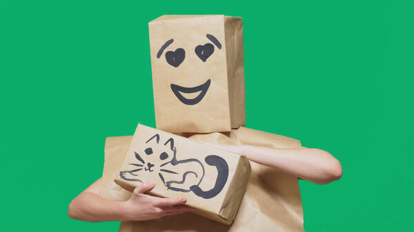 concept of emotions, gestures. a man with a package on his head, with a painted emoticon, smile, loving eyes. plays with a cat drawn on the box.