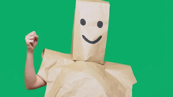 Concepto de emociones, gestos. un hombre con bolsas de papel en la cabeza, con un emoticono pintado, sonrisa, alegría — Foto de Stock