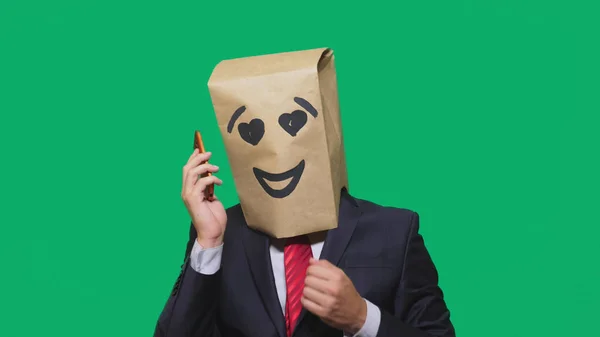 Koncepcja emocje, gesty. człowiek z torby papierowe na głowie, malowane emotikon, uśmiech, radość, miłość. rozmowy na telefon komórkowy — Zdjęcie stockowe