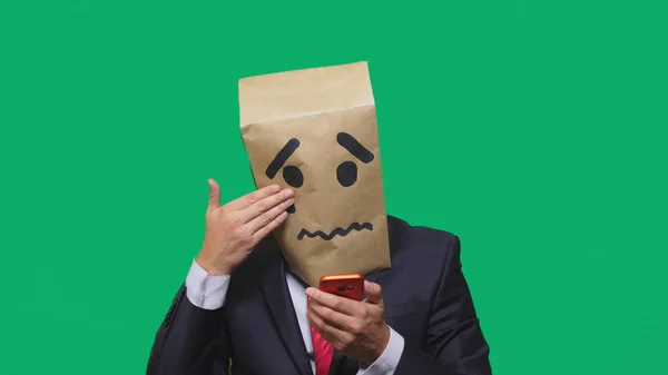 Концепція емоцій, жестів. чоловік з пакетом на голові, з пофарбованим смайлик плаче, сумно, розмовляє по телефону — стокове фото