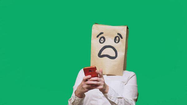 concept of emotions, gestures. a man with paper bags on his head, with a painted emoticon, fear. talking on a cell phone