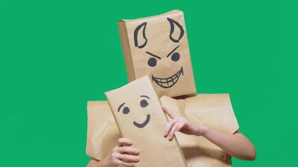 Concept of emotions, gestures. a man with a package on his head, with a painted emoticon devil, crafty, gloating. plays with the child drawn on the box. childs deception, naivety — Stock Photo, Image