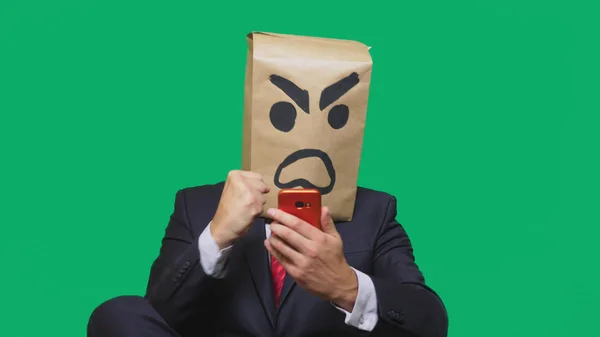 Pojmu emoce, gesta. muž s balíčkem na hlavě, s malovanými smajlík, agresivní, vztek. mluví o mobilní telefon — Stock fotografie