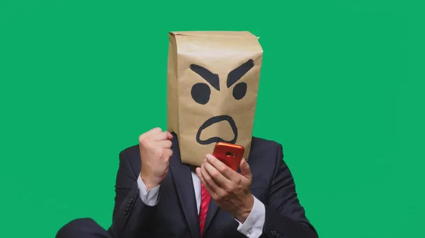 Begreppet känslor, gester. en man med ett paket på huvudet, med en målad smiley aggressiv, arg. talar i en mobiltelefon — Stockfoto