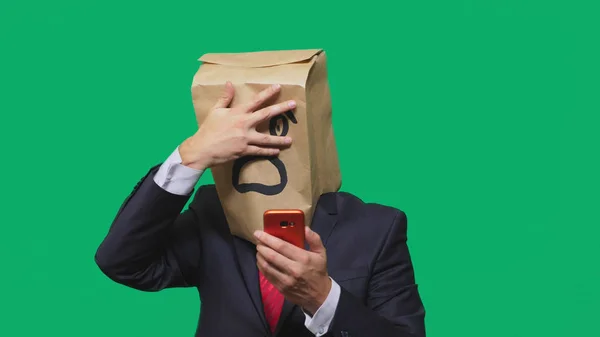 Concept van emoties, gebaren. een man met papieren zakken op zijn hoofd, met een geschilderde emoticon, vrees. praten op een mobiele telefoon — Stockfoto