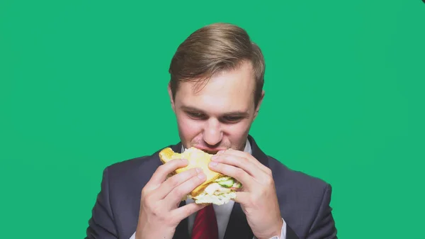 Liikemies syö voileipää vihreällä taustalla. nopea lounas käsite — kuvapankkivalokuva