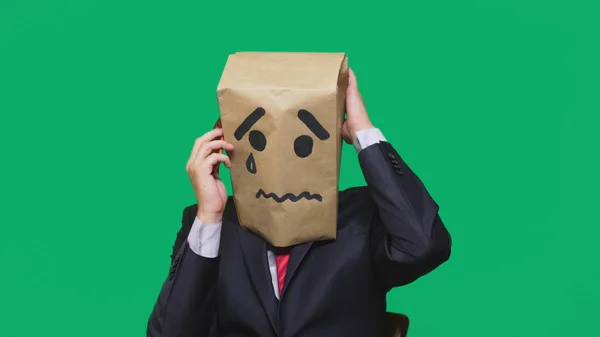 Begreppet känslor, gester. en man med ett paket på huvudet, med en målad smiley gråt, ledsen, prata i telefon — Stockfoto
