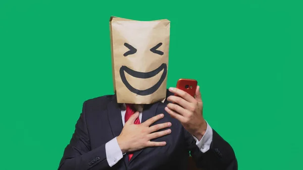 Konzept der Emotionen, Gesten. ein Mann mit Papiertüten auf dem Kopf, mit einem aufgemalten Emoticon, Lächeln, Freude. Telefonieren auf dem Handy — Stockfoto