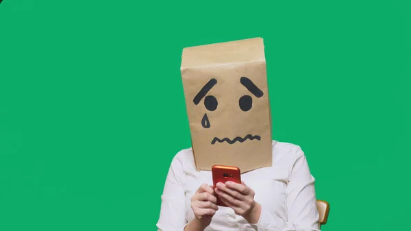 Concept van emotie, gebaren. een man met een pakket op zijn hoofd, met een geschilderde smiley huilen, triest, praten aan de telefoon — Stockfoto