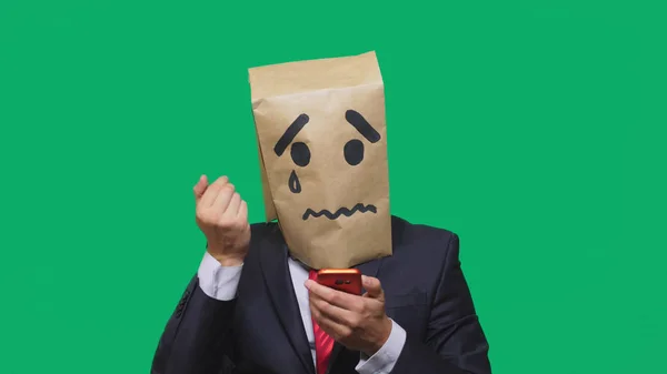 Концепция эмоций, жестов. мужчина с пакетом на голове, с нарисованной надписью плачет, грустит, разговаривает по телефону — стоковое фото