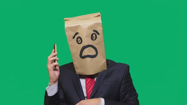 Koncepcja emocje, gesty. człowiek z torby papierowe na głowie, z malowane emotikon, strach. rozmowy na telefon komórkowy — Zdjęcie stockowe