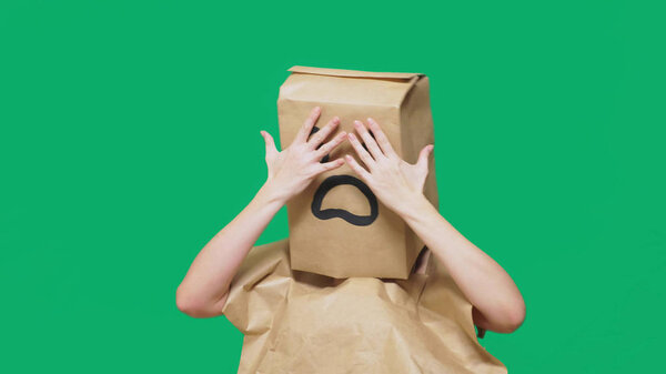 concept of emotions, gestures. a man with paper bags on his head, with a painted emoticon, fear.