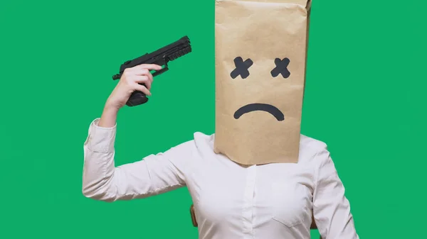 Concept van emotie, gebaren. een man met een pakket op zijn hoofd, met een geschilderde smiley, uitgeput, moe, houdt een pistool in zijn hand. Het concept van zelfmoord. — Stockfoto