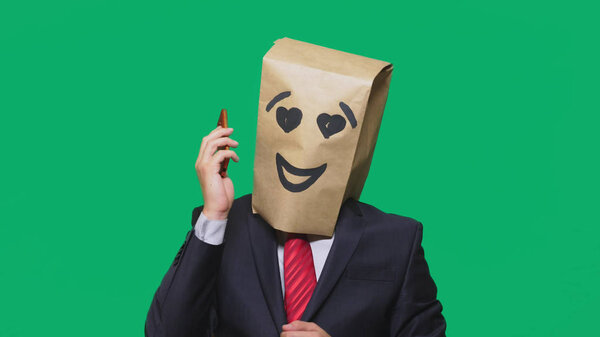 concept of emotions, gestures. a man with paper bags on his head, with a painted emoticon, smile, joy, love. talking on a cell phone
