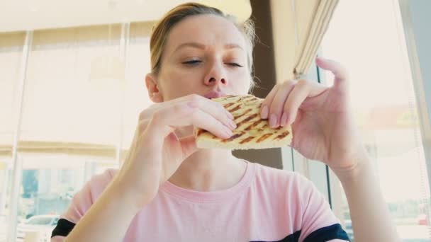 Una mujer guapa comiendo un sándwich y tomando café en un café de comida rápida. comida rápida . — Vídeos de Stock